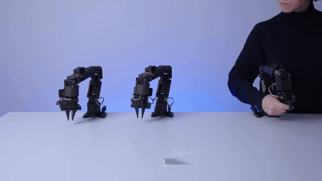 Operator moves the ElRobot leader arm by hand while two follower arms mirror the motion